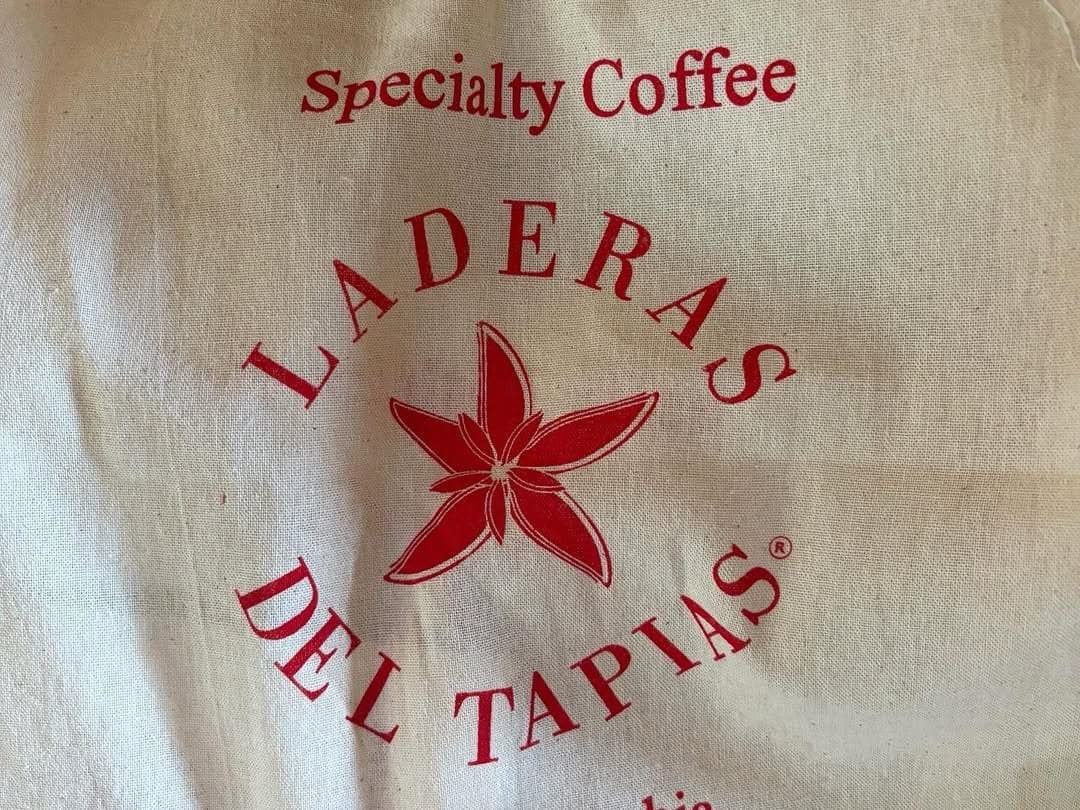 A cream coloured sack printed Specialty Coffee, Laderas del Tapias, with a red flower mark